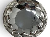 a silver bowl on a white surface with a white background