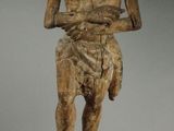 an old wooden statue of a man standing on a rock