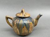 a small teapot with a lid on a table
