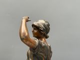 statue en bronze représentant une femme tenant une raquette de tennis dans la main droite