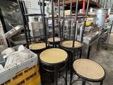 Plusieurs chaises et tabourets sont empilés dans un entrepôt
