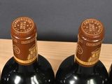 three bottles of wine are in a wooden holder on a table