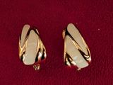 two pairs of gold toned earrings on a red surface