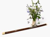 a vase with flowers and a baseball bat on a white surface