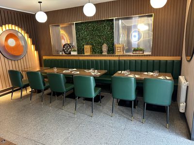 tables and chairs in a restaurant with a large painting on the wall