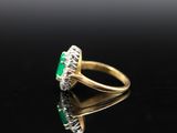 an oval emerald and diamond ring on a black surface