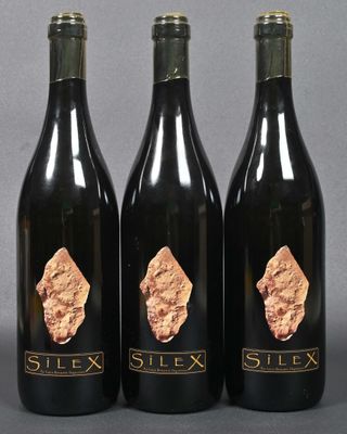 three bottles of wine with gold foil on them sitting on a table