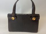 un petit sac à main noir avec des finitions dorées sur la poignée