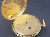 an antique pocket watch sitting on top of a table next to a blue surface