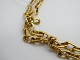 gros plan d'un collier à chaîne en or sur une surface blanche