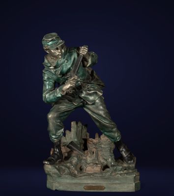 une statue en bronze représentant un soldat debout sur un rocher, un fusil à la main