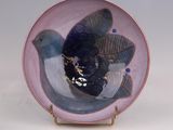 a plate with a bird on it sitting on a stand