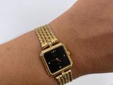 an image of a woman ' s wrist with a gold watch on it
