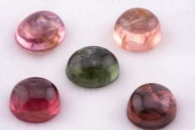 six pierres précieuses de couleurs différentes sont disposées en ligne sur une surface blanche