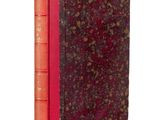 an old book with a red cover sitting on top of a white surface