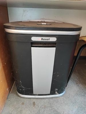 une poubelle noire et blanche à côté d'une étagère en bois