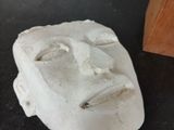 cement sculpture of a face on a table next to a wooden block