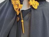 a mannequin dressed in a cape with a gold necklace and earrings