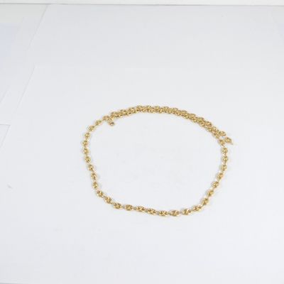 un bracelet en chaîne dorée posé sur une surface blanche, à côté d'une paire de ciseaux