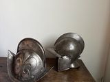 deux casques métalliques posés sur une table en bois dans une pièce