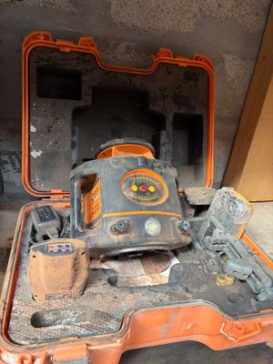 une mallette orange contenant un outil, posée par terre