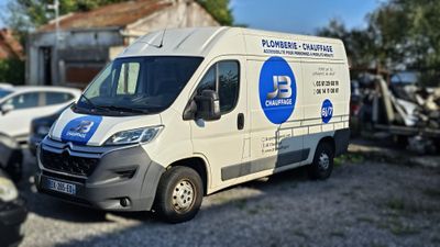 une camionnette blanche garée sur un parking à côté d'un bâtiment