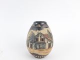 a small vase with a picture of a barn on it