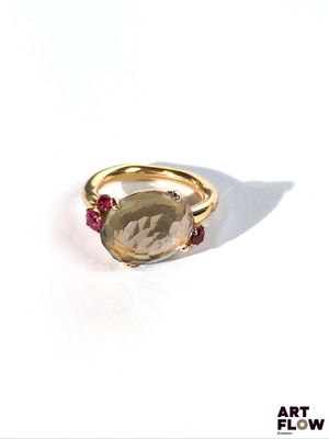 une image représentant une bague en or sertie d'une pierre à facettes entourée de rubis