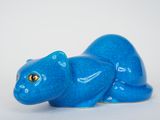 une figurine de chat bleu posée sur une surface blanche