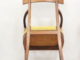 a wooden chair that has a yellow seat on it