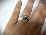 a woman ' s hand with a ring and a pearl