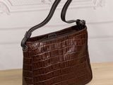 a brown crocodile skin handbag on a wooden table