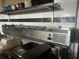stainless steel counter top in a commercial kitchen with dishes on the shelves