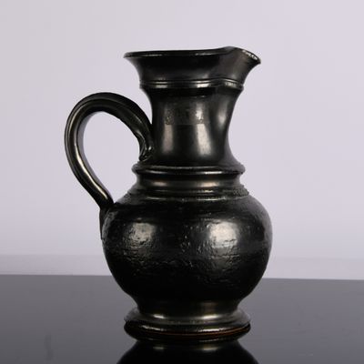un vase noir posé sur une table, sur fond blanc