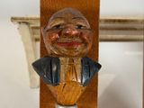 a wooden sculpture of a man holding a bottle opener