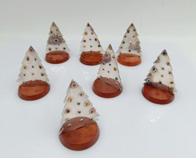 six small white christmas trees with brown bases on a white surface