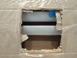 a hole in a cardboard box with a blue tape on it