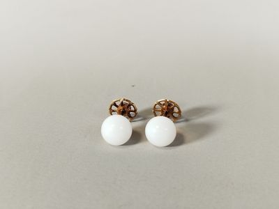 une paire de boucles d'oreilles en perles blanches posées sur une surface blanche