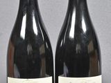 two bottles of red wine sitting next to each other on a table