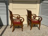 two wooden chairs sitting next to each other in front of a building