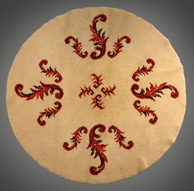 une image représentant un tapis rond orné de motifs rouges et noirs