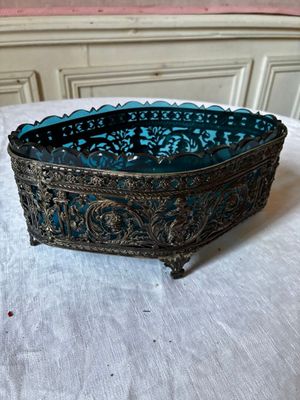 un vieux saladier en verre bleu posé sur une table blanche