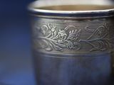 a silver cup with a handle on a blue background