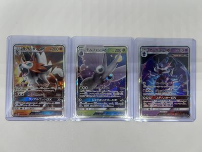 three pokemon cards in plastic cases on a white surface