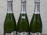 trois bouteilles de champagne posées sur une table en bois