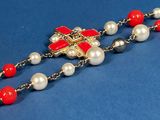 an image of a red and white necklace with pearls on a blue background