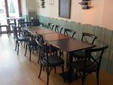 Dans un restaurant au sol en parquet, des tables et des chaises sont alignées.