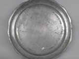 an old silver plate on a white surface with a gray background