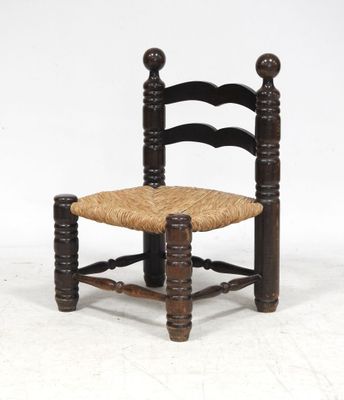 une image représentant une chaise en bois avec une assise tressée, posée sur une surface blanche