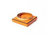 une boîte orange sur laquelle est posé un bracelet, posée sur une surface blanche